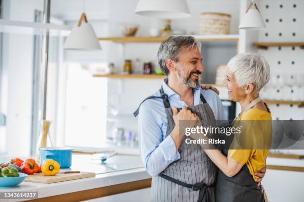 ロマンチックな成熟したカップル、台所で踊る - middle aged couple cooking ストックフォトと画像
