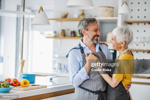 romantic mature couple, dancing in the kitchen - two houses side by side stock pictures, royalty-free photos & images