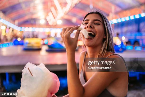 cute woman eating cotton candy at the funfair - cotton candy stock pictures, royalty-free photos & images