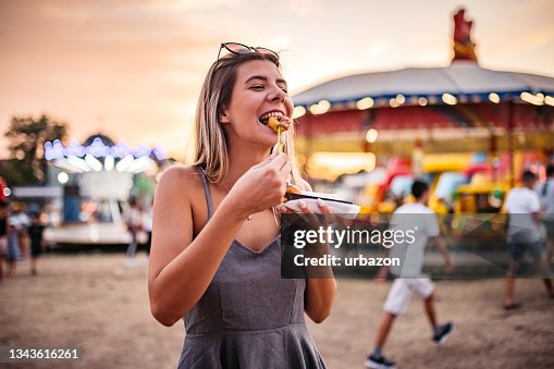 Femme mignonne mangeant de petits beignets à la fête foraine Femme mignonne mangeant de petits beignets à la fête foraine
