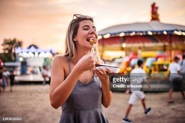 donna carina che mangia piccole ciambelle al luna park - festival tradizionale foto e immagini stock