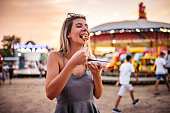 Cute Woman eating small donuts at the Funfair