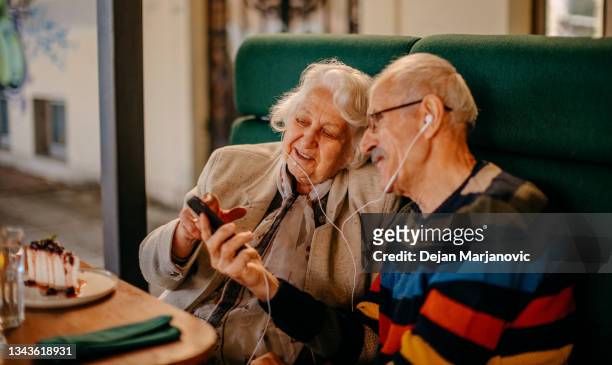 old couple in restaurant - sharing headphones stock pictures, royalty-free photos & images