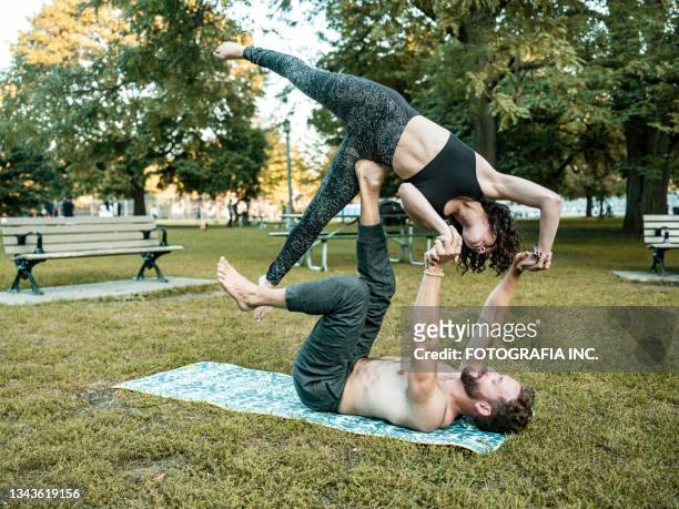 young couple practising acro yoga in the park - acroyoga stock pictures, royalty-free photos & images