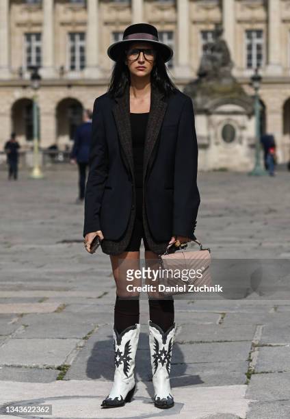 Guest is seen wearing a black jacket, black hat, white cowboy boots with a YSL pink bag outside the Christian Dior show during Paris Fashion Week S/S...