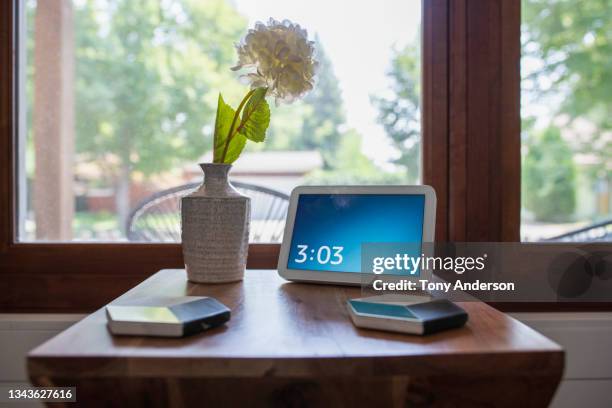 side table near bright window with digital clock, flower vase and coasters - digitaluhr stock-fotos und bilder