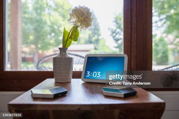 side table near bright window with digital clock, flower vase and coasters - digital clock stock pictures, royalty-free photos & images