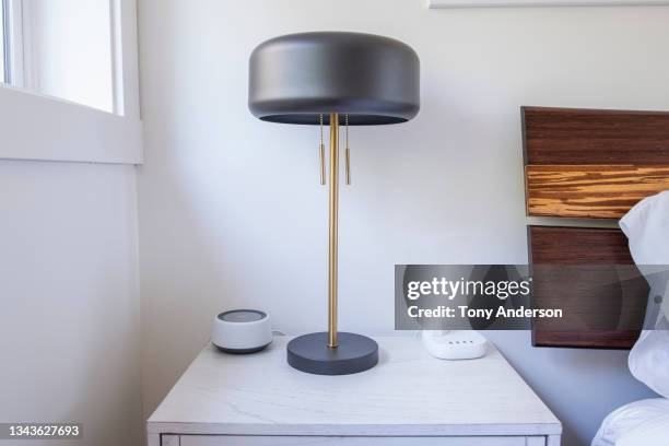 bedside table with lamp, smart speaker and charging dock - lampada elettrica foto e immagini stock