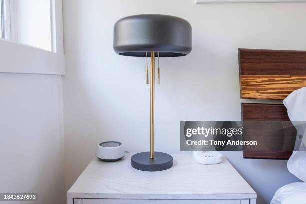 bedside table with lamp, smart speaker and charging dock - bedside table stock pictures, royalty-free photos & images