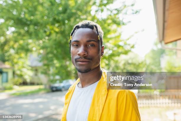 young man standing in yard of home on residential street - belle black photos et images de collection