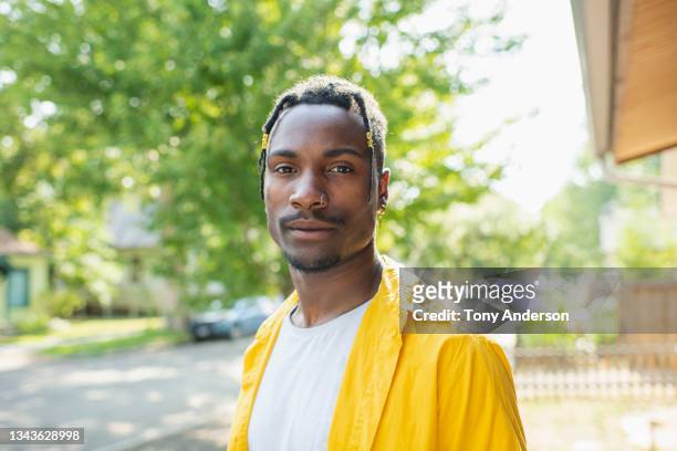 young man standing in yard of home on residential street - american man stockfoto's en -beelden