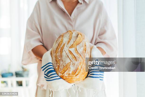 woman holding fresh baked sourdough bread - loaf of bread stock pictures, royalty-free photos & images
