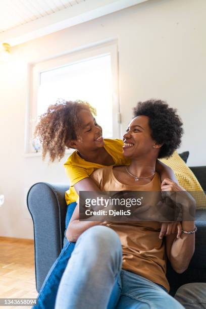 happy mother and daughter relaxing at home and embracing. - african american watching tv stock pictures, royalty-free photos & images