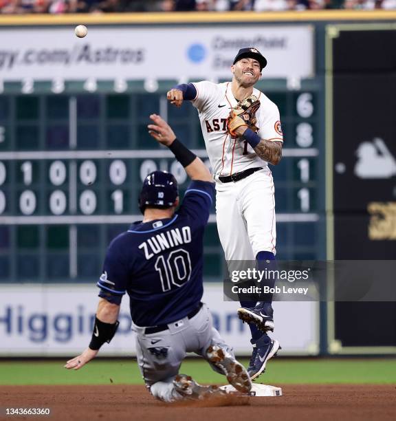 Carlos Correa of the Houston Astros turns a double play in the seventh inning as Mike Zunino of the Tampa Bay Rays slides into second base at Minute...