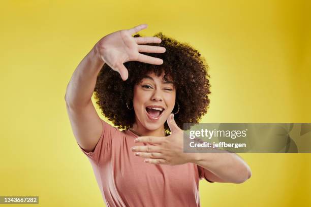 tiro de estúdio de uma jovem atraente fazendo uma moldura de dedo contra um fundo amarelo - dedos fazendo moldura - fotografias e filmes do acervo