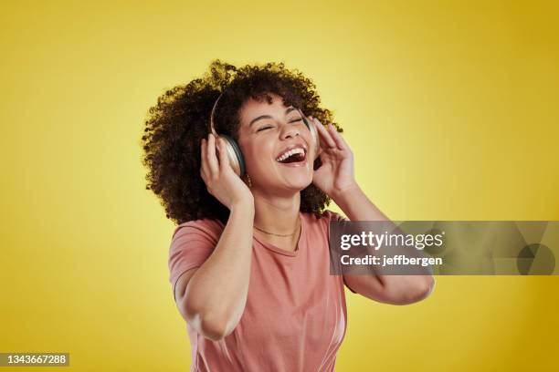 studio shot of an attractive young woman using headphones against a yellow background - podcast headphones stock pictures, royalty-free photos & images