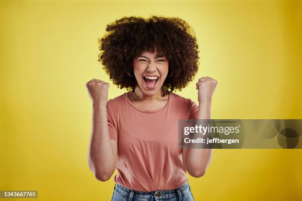 studioaufnahme einer attraktiven jungen frau, die aufgeregt vor gelbem hintergrund aussieht - celebrating win stock-fotos und bilder