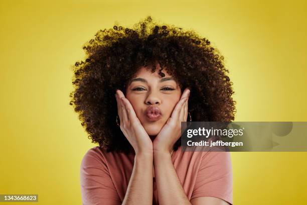 studio shot of an attractive young woman posing against a yellow background - puckering stock pictures, royalty-free photos & images