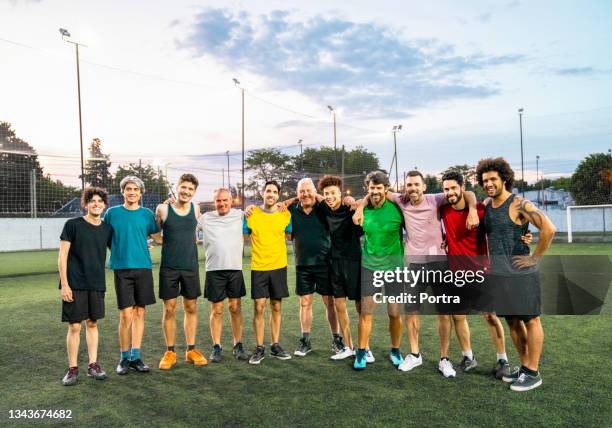 smiling male soccer team standing with arms around - football team stock pictures, royalty-free photos & images