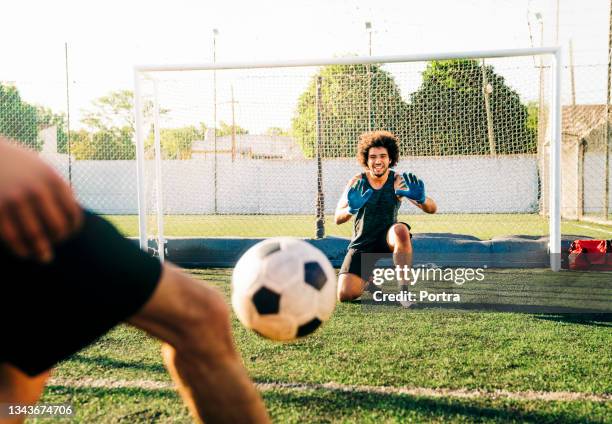 männlicher torwart beim fußballspielen mit freund auf dem feld - amateur stock-fotos und bilder