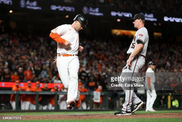 Buster Posey of the San Francisco Giants runs home to score on a wild pitch by Joe Mantiply of the Arizona Diamondbacks in the sixth inning at Oracle...