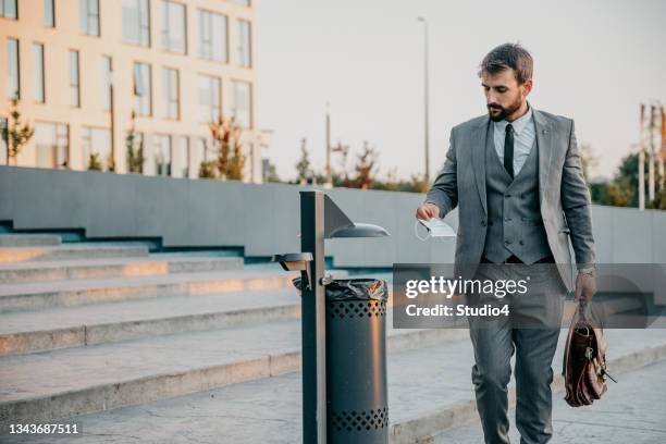 businessman taking off and throwing a protective face mask - waste wealth stock pictures, royalty-free photos & images