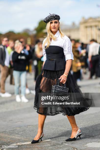 Valentina Ferragni wears a gray and black leopard print pattern beret / hat, a white shirt, a black shoulder-off t-shirt, a black shiny leather...