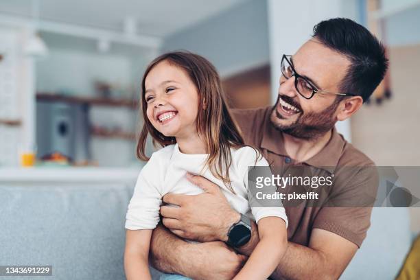 padre feliz sosteniendo a su pequeña hija - fathers day fotografías e imágenes de stock