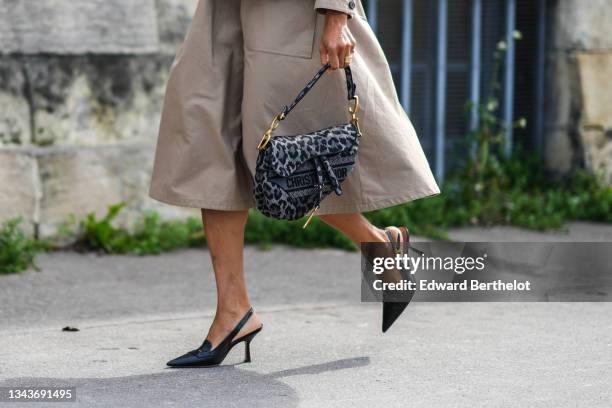 Tamu McPherson wears a brown blazer jacket, a matching brown knees skirt, a black and gray leopard pattern Saddle handbag from Dior, gold rings,...