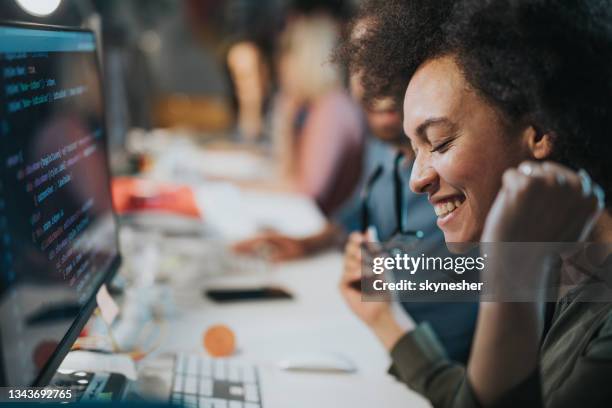 cheerful african american computer programmer celebrating success in the office. - happy programmer stock pictures, royalty-free photos & images