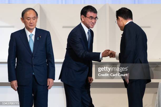 Outgoing Prime Minister Yoshihide Suga looks on as Japan's Regulatory Reform and Vaccine Minister Taro Kono bumps fists with former Japanese Foreign...