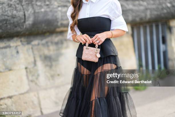 Negin Mirsalehi wears a white puffy short sleeves body / shirt, a black shoulder-off top, a black high waist tulle long pleated / accordion skirt, a...