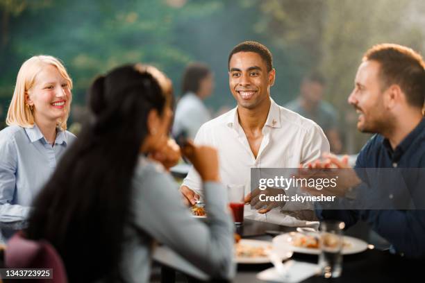 group of happy colleagues talking while enjoying in lunch at a restaurant. - business lunch outside stock pictures, royalty-free photos & images