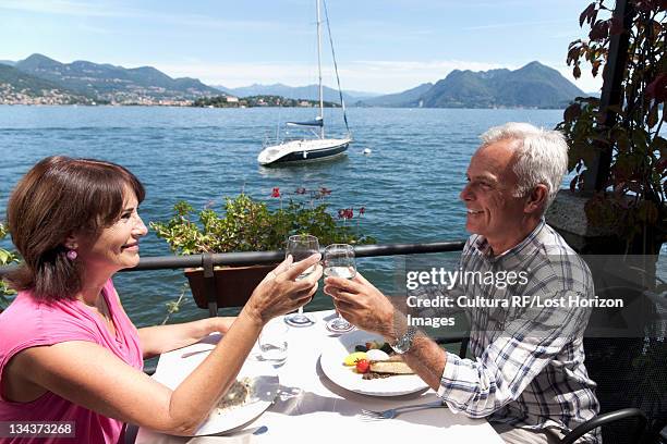 older couple toasting with wine outdoors - coppie cibo food bistrot foto e immagini stock