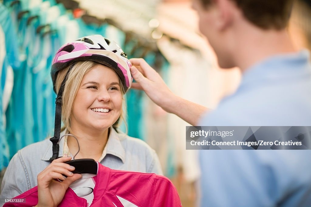 Woman trying on bicycle helmet in shop