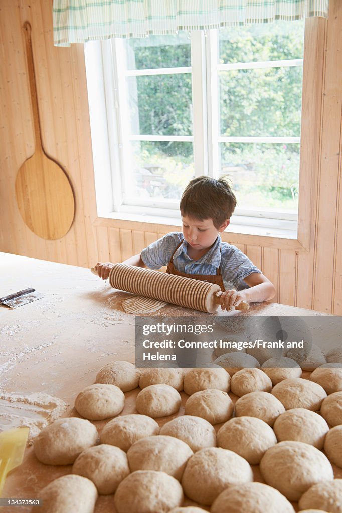 Boy rolling out bread with rolling pin