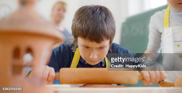 boy rolling clay in classroom - rolling pin stock pictures, royalty-free photos & images