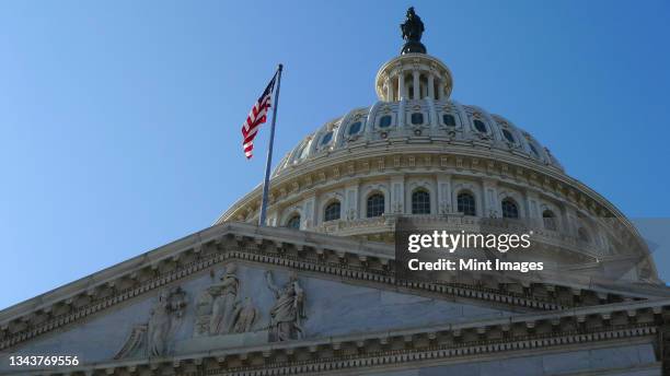 usa capitol building dome with american flag flying. - edificio federal fotografías e imágenes de stock