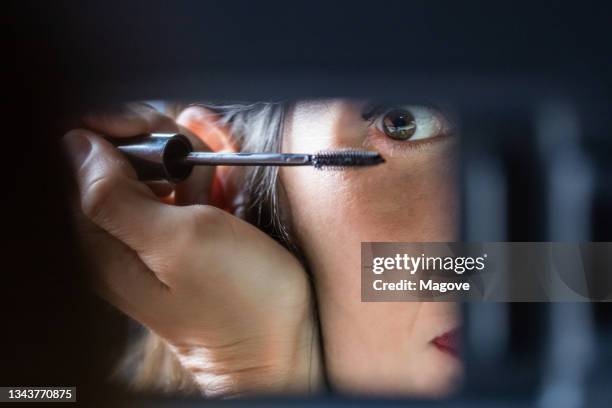 careless woman applying mascara on her eyes while driving a car. - rear view mirror eyes stock pictures, royalty-free photos & images