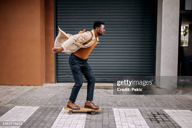 giovane uomo d'affari bello che guida skateboard sulla strada della città - skateboard foto e immagini stock