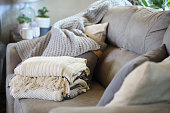 Stack of a variety of soft knit throw blankets stacked on a grey couch in a farmhouse style living room