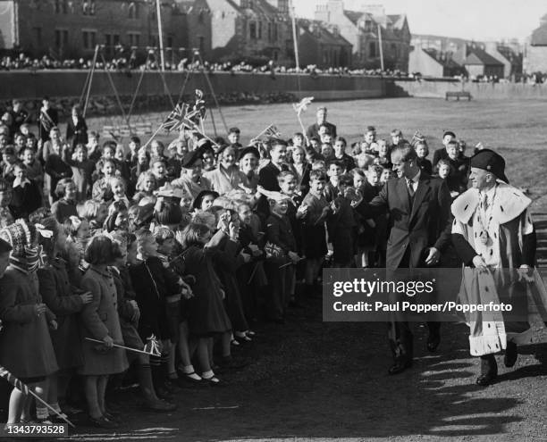 Prince Philip, Duke of Edinburgh , accompanied by George Burgess, Provost of Lerwick Town Council, is cheered by school children as he arrives to...