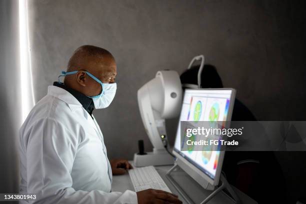 optometrist examing patient's eyes - eye scan stock pictures, royalty-free photos & images