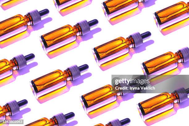 trendy pattern made of beauty product  facial serums or natural essential oil in cosmetic bottle with dropper and bright  shadow on white background. - oil bottle stock pictures, royalty-free photos & images