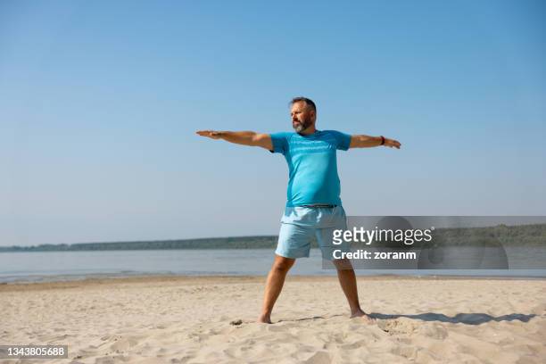 homme faisant de l’exercice sur la plage par temps clair - fat guy on beach photos et images de collection
