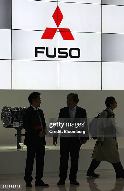 Visitors walk in front of the Mitsubishi Fuso Truck & Bus Corp. Logo at the Tokyo Motor Show 2011 in Tokyo, Japan, on Thursday, Dec. 1, 2011. The...