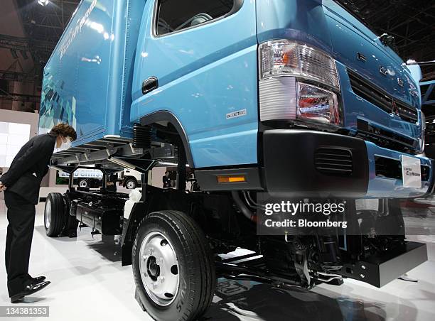 Visitor looks at Mitsubishi Fuso Truck & Bus Corp.'s Canter Eco Hybrid truck is displayed at the Tokyo Motor Show 2011 in Tokyo, Japan, on Thursday,...