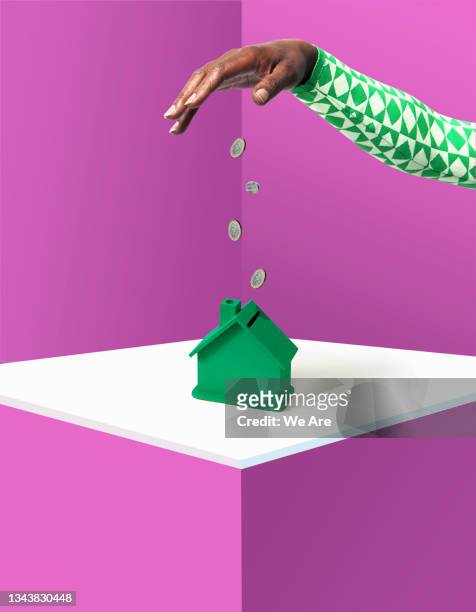 hand dropping money into house - money abstract ストックフォトと画像