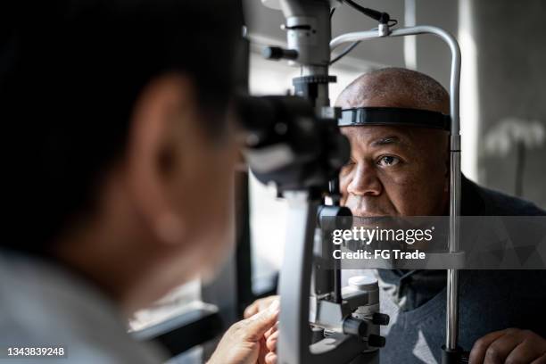 oftalmologo che esamina gli occhi del paziente - optometria foto e immagini stock