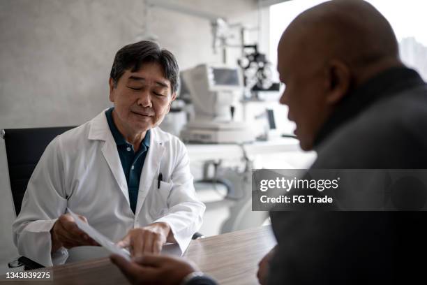 doctor talking to patient showing eye exams during medical appointment - eye doctor and patient stock pictures, royalty-free photos & images